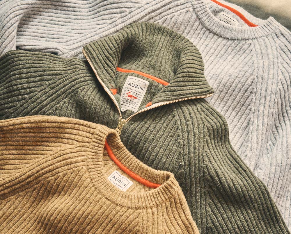 Men's knitwear styles including grey crewneck sweater, sand jumper and olive green zipped funnel neck knit